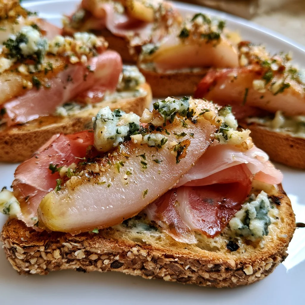 Pear prosciutto crostini garnished with blue cheese and arugula, showcasing flavors.